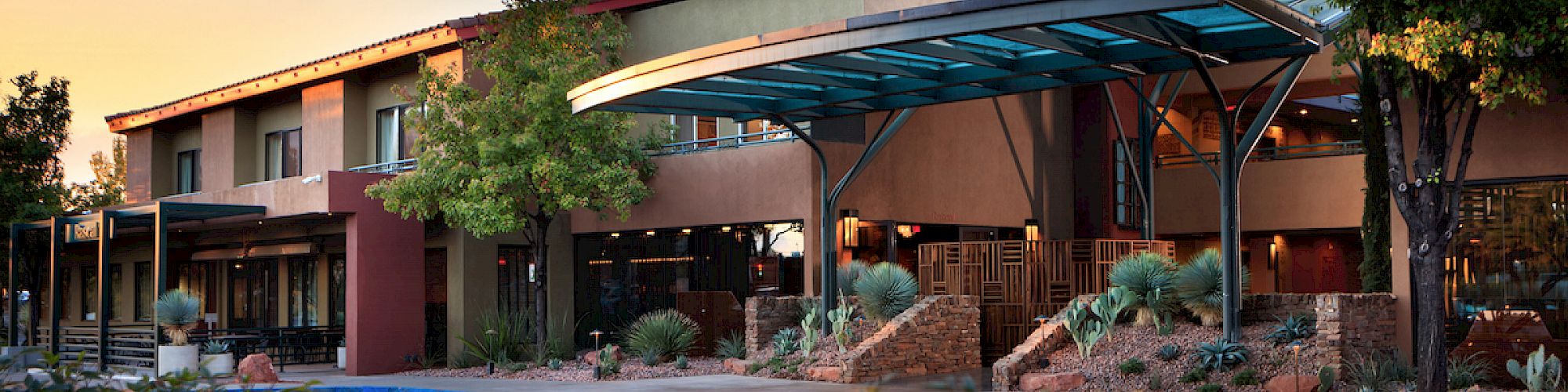 This image shows the exterior of a building named "The Wilde Resort and Spa," featuring a modern canopy, desert landscaping, and surrounding greenery.