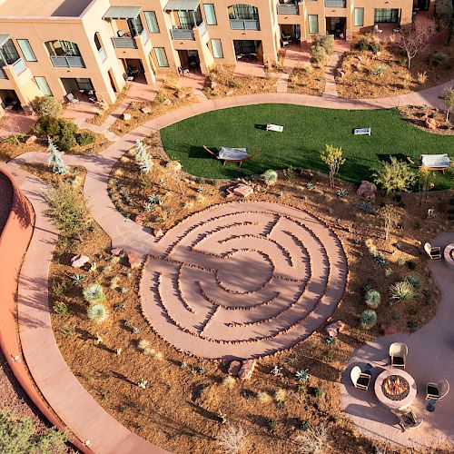 An aerial view shows a courtyard with a labyrinth, green lawn, benches, and seating areas. The scene includes pathways and landscaped greenery.