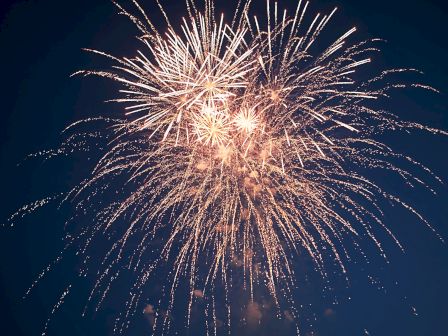 A burst of golden fireworks illuminates the night sky, creating a festive and celebratory atmosphere.